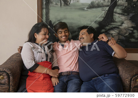 Happy family sitting together on the couch in their living room at home. 59772930
