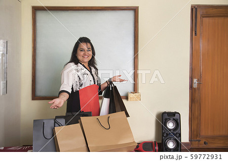 Portrait of a young woman standing around lots of shopping bags. 59772931