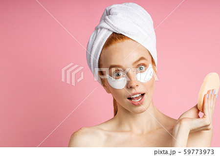 Shot of young woman applies eye patches and holding cosmetic sponge 59773973
