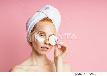 Shot of young woman applies eye patches and holding cosmetic sponge 59773980