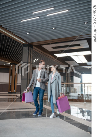 Couple carrying shopping bags feeling happy after shopping together Couple carrying shopping bags feeling happy after shopping together 59774076