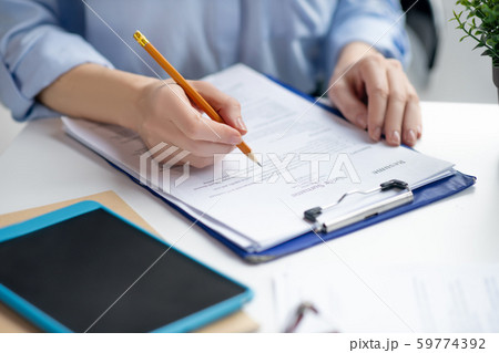 Close up of businesswoman filling tax declaration while sitting at the table 59774392