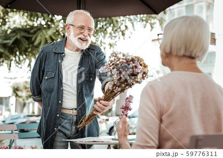 Joyful delighted man giving flowers to an elderly woman Joyful delighted man giving flowers to an elderly woman 59776311