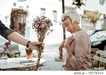 Joyful nice aged woman receiving beautiful flowers 59776314