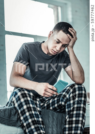 Depressed young man holding his smartphone in the hand Depressed young man holding his smartphone in the hand 59777462