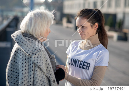 Grey-haired homeless pensioner talking to volunteer in the street 59777494