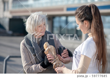Homeless pensioner taking some food and tea from kind volunteer 59777685
