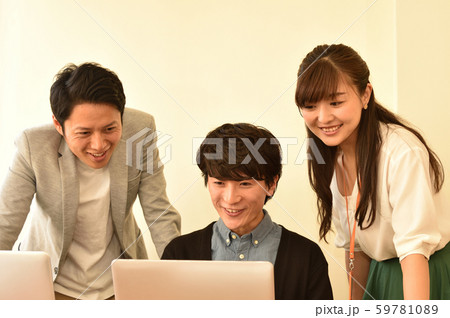 パソコンの画面を見ながら談笑する男女　３人　<ビジネスカジュアル/プロジェクトチーム> 59781089