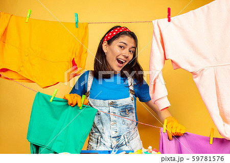 Funny and beautiful housewife doing housework on yellow background 59781576