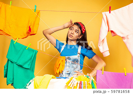 Funny and beautiful housewife doing housework on yellow background Funny and beautiful housewife doing housework on yellow background 59781658