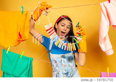 Funny and beautiful housewife doing housework on yellow background Funny and beautiful housewife doing housework on yellow background 59781750