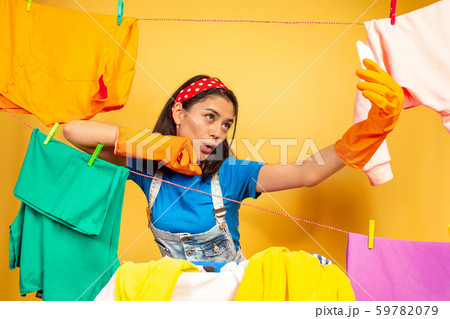 Funny and beautiful housewife doing housework on yellow background 59782079