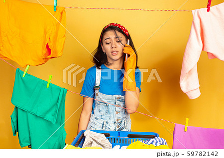 Funny and beautiful housewife doing housework on yellow background 59782142