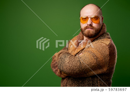 Bald man in sweater with arms crossed on empty green background 59783697
