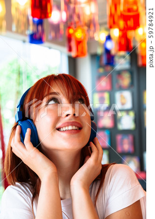 Happy girl listens to music on headphones in cafe 59784921