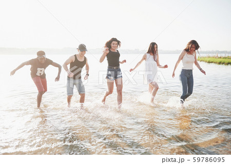 Happy friends have fun on the beach - Young people playing in open air water on summer holidays 59786095