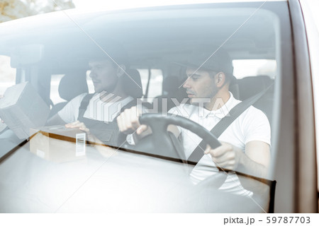 Delivery company employees driving a cargo vehicle Delivery company employees driving a cargo vehicle 59787703