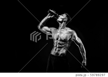Muscular man with protein drink in shaker over dark background Muscular man with protein drink in shaker over dark background 59789297