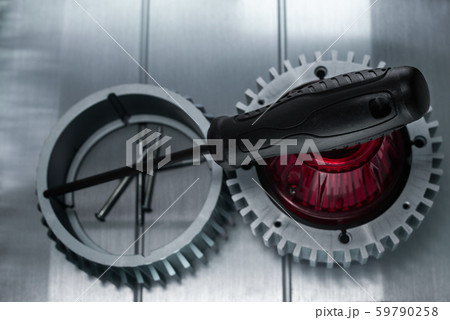 Professional reinforced black matt screw driver placed on a gearwheel. View from the top. Professional reinforced black matt screw driver placed on a gearwheel. View from the top. 59790258
