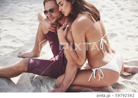 A beautiful couple relaxing on the sandy beach, wearing bathing clothes. Romantic atmosphere 59792562