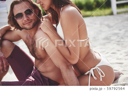 Beautiful sexy couple guy and girl wearing swimwear when on the beach. Romantically lying on the 59792564
