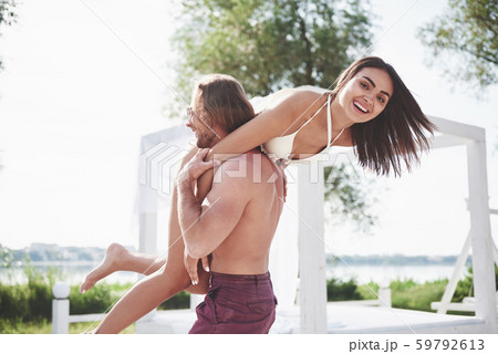Beautiful young people are fond of it. A man holds a woman on his shoulders, they are playful and 59792613