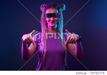 Happy girl with pigtails in sunglasses looking at camera in neon light Happy girl with pigtails in sunglasses looking at camera in neon light 59792779