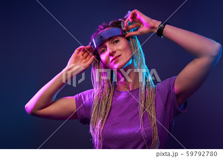 Young woman with pigtails in sunglasses looking at camera in neon light 59792780