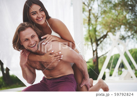 A beautiful couple relaxing on the sandy beach, wearing bathing clothes. Romantic atmosphere 59792824