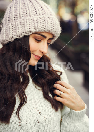 Cute brunette in a white sweater in a city 59800077
