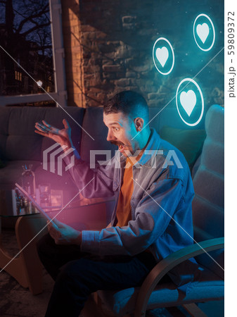Man using gadget and receive neon notifications at home at night 59809372