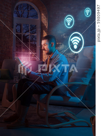 Man using gadget and receive neon notifications at home at night Man using gadget and receive neon notifications at home at night 59809497