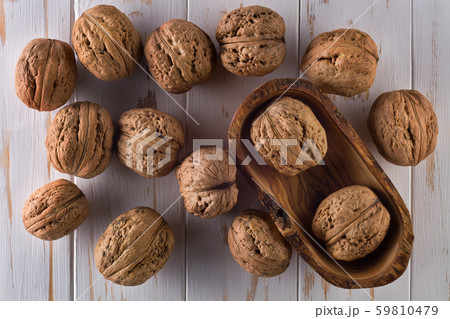Top view photo of whole walnuts on painted white wooden table in bowl 59810479