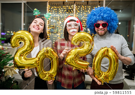 Cheerful colleagues with inflatable numbers standing in front of camera 59811555