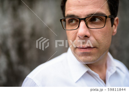 Handsome Persian businessman against concrete wall outdoors 59811844