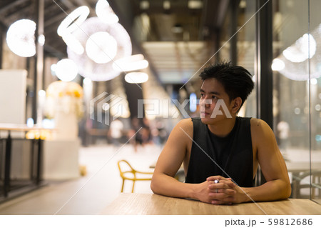 Young handsome Asian man thinking in the restaurant at night Young handsome Asian man thinking in the restaurant at night 59812686