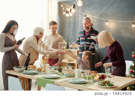 Cute little girl passing bowl with salad to her great grandma by festive table 59814920