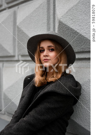 Portrait of beautiful woman wearing hat and gray coat. Outdoor portrait in city Portrait of beautiful woman wearing hat and gray coat. Outdoor portrait in city 59818079