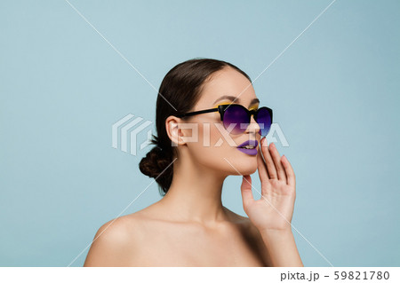 Portrait of beautiful young woman with bright make-up isolated on blue studio background 59821780