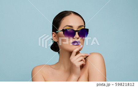 Portrait of beautiful young woman with bright make-up isolated on blue studio background Portrait of beautiful young woman with bright make-up isolated on blue studio background 59821812