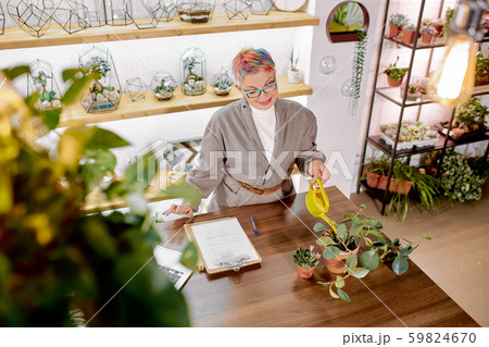 Careful senior business woman watering plants in pot in her office 59824670