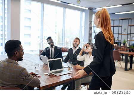 Auburn haired leader woman explaining business idea to foreign representatives 59825230