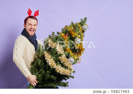 Man in red christmas horn holding Christmas tree Man in red christmas horn holding Christmas tree 59827465