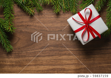 Top view of green spruce twigs with gift box with red ribbon on walnut wood surface 59837159