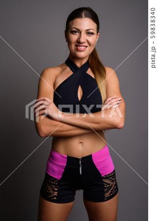 Young beautiful woman ready for gym against gray background Young beautiful woman ready for gym against gray background 59838340