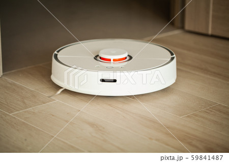 Smart House. Vacuum cleaner robot runs on wood floor in a living room. 59841487