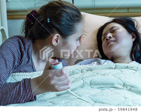 Asian mother and daughter laying in hosital bed, 59841948