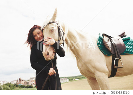 A happy girl communicates with her favorite horse. The girl loves animals andhorseback riding 59842816