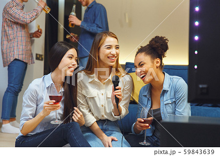 Group of friends having party indoors fun together girls laughing Group of friends having party indoors fun together girls laughing 59843639