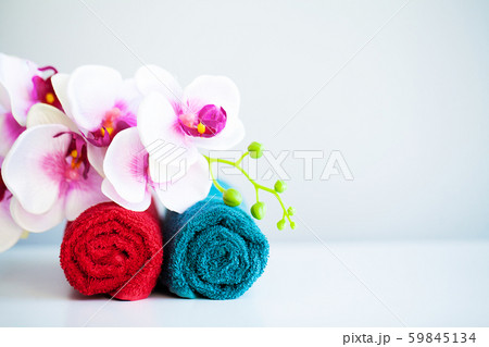 Colored towels and orchid on white table with copy space on bath room background. Colored towels and orchid on white table with copy space on bath room background. 59845134